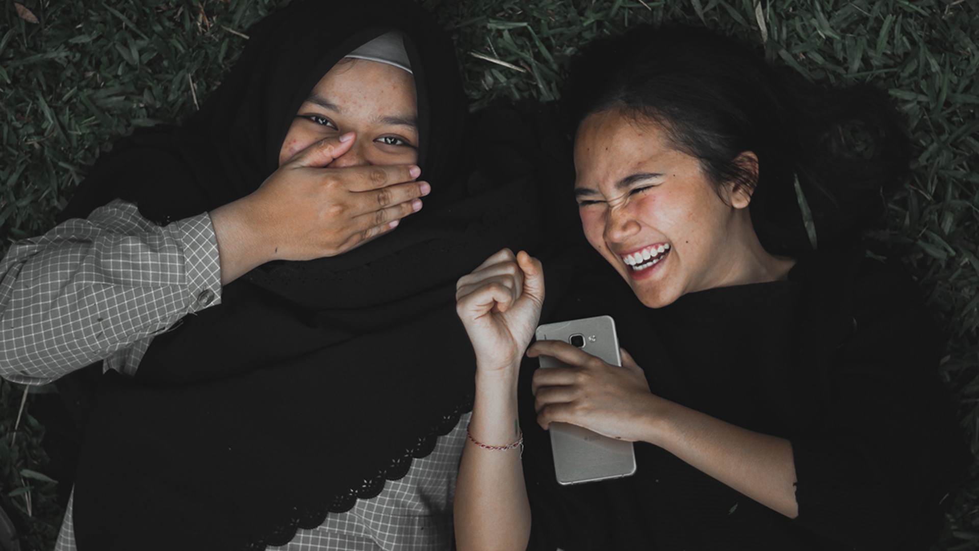 Zwei lachende Teenager mit einem Handy
