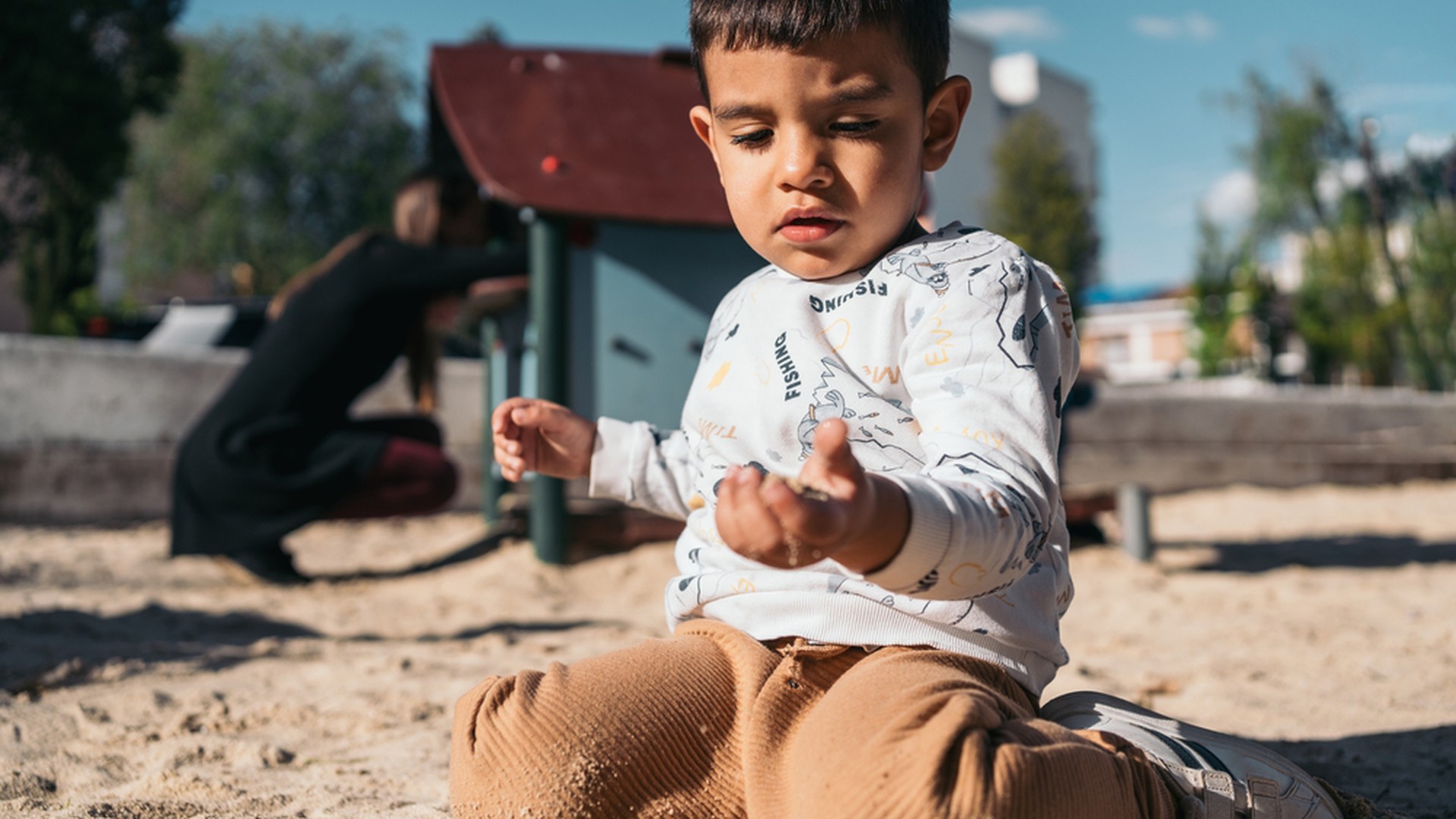 Kind spielt vertieft mit Sand in den Händen