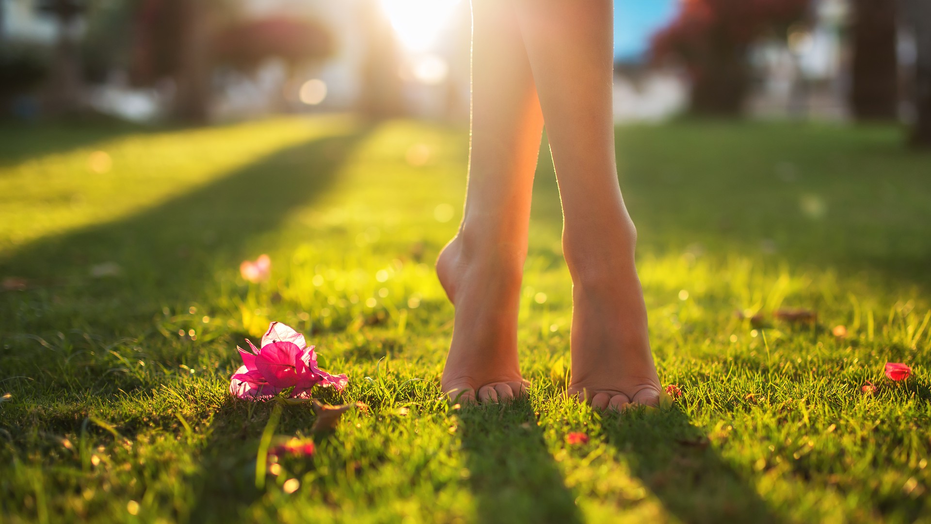 Füße eines Teenagers tanzen bei Sonnenschein im Gras