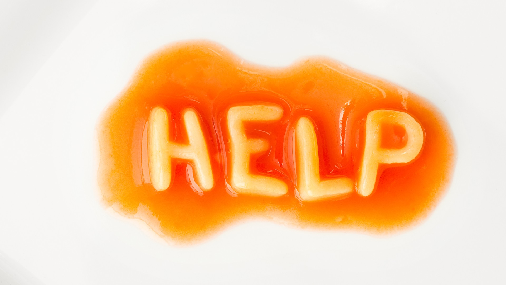 Tomatensauce und Buchstabennudeln formen das Wort Help